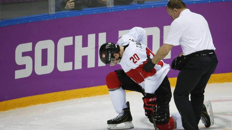 Canada forward John Tavares is helped up off the ice...