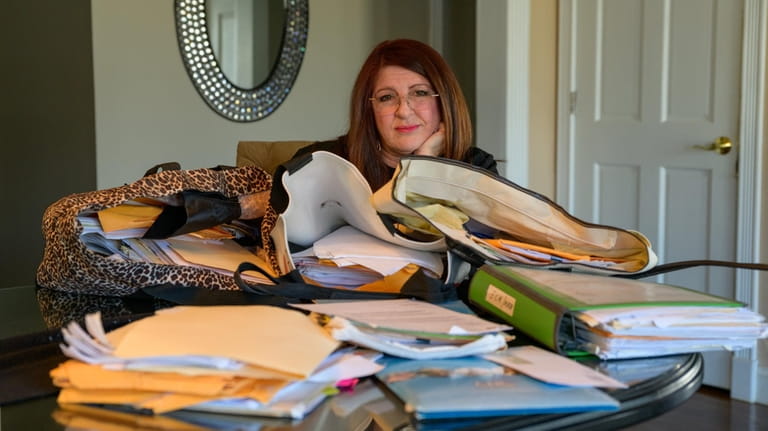 Hallie Maggi sits at a table with stacks of documents from...
