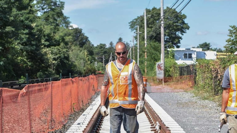 A LIRR worker walks along the first section of rail...