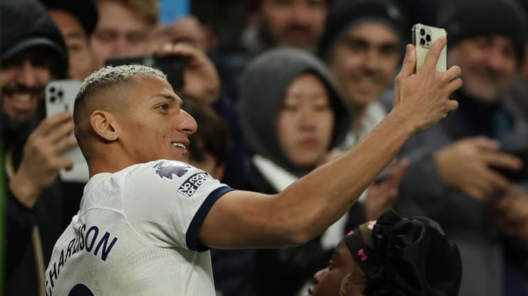 Tottenham's Richarlison takes a selfie with supporters at full time...