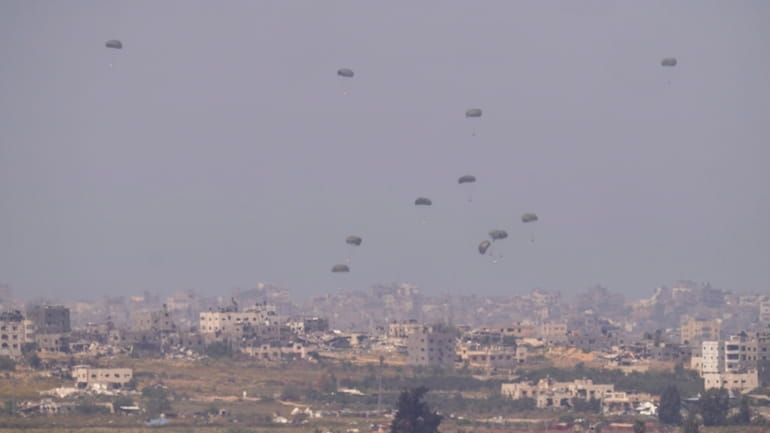Parachutes drop supplies into the northern Gaza Strip, seen from...