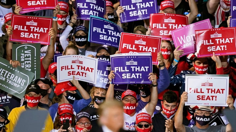 Supporters of President Donald Trump hold up signs as he...