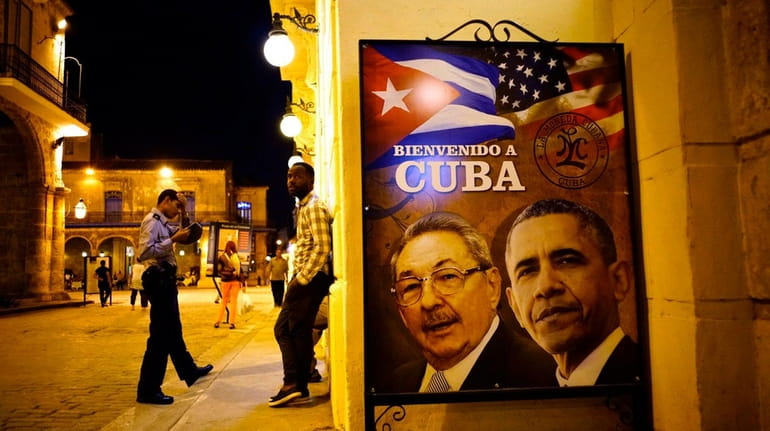 A poster features portraits of Cuba's President Raúl Castro, left,...