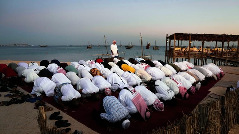Men pray in Katara beach, Doha, Qatar, Monday, Nov. 28,...