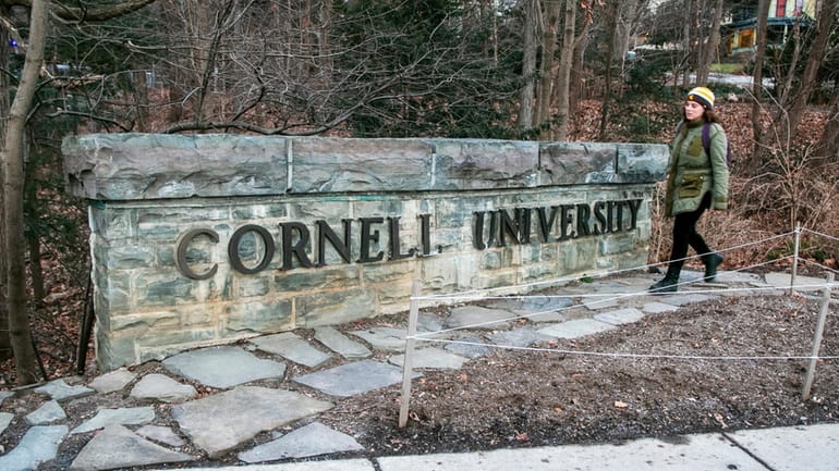 A woman walks by a Cornell University sign on the...