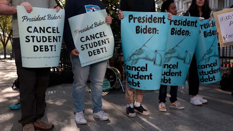 Activists hold signs at a student loan forgiveness rally on...