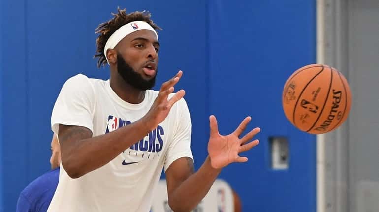 Knicks center Mitchell Robinson reaches for a throw during training...