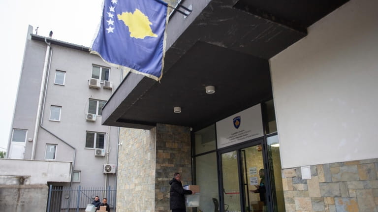Kosovo election officials carry the ballot boxes and polling station...
