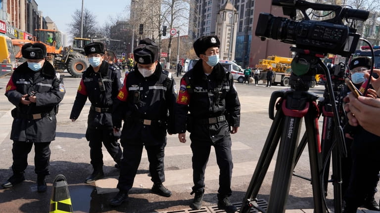 Chinese police officers prepare to push journalists away from the...