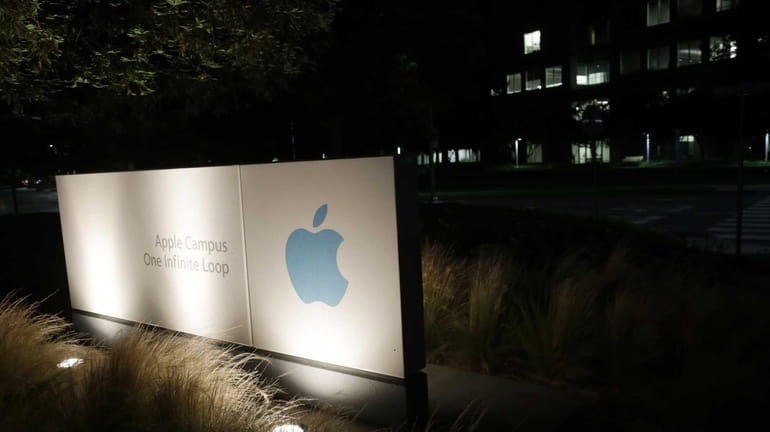 A sign displays the Apple logo outside of the company's...