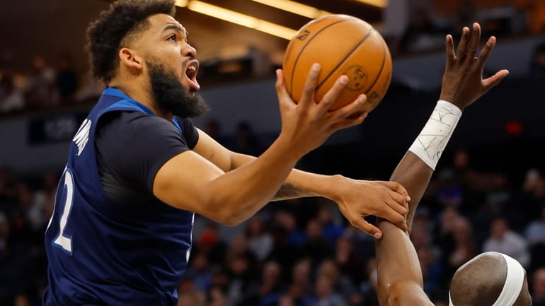 Minnesota Timberwolves forward Karl-Anthony Towns, left, goes to the basket...