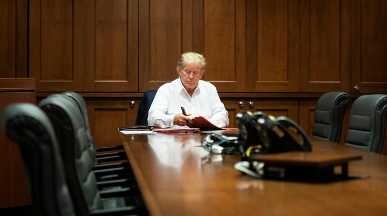 President Donald Trump works in his conference room at Walter...
