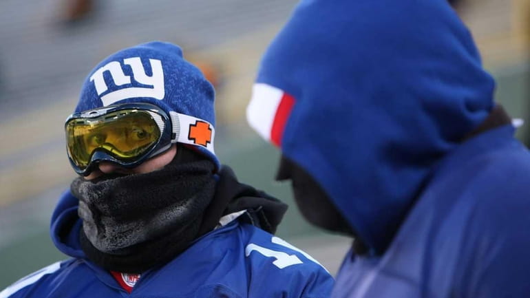 New York Giants fans sit bundled up as they await...