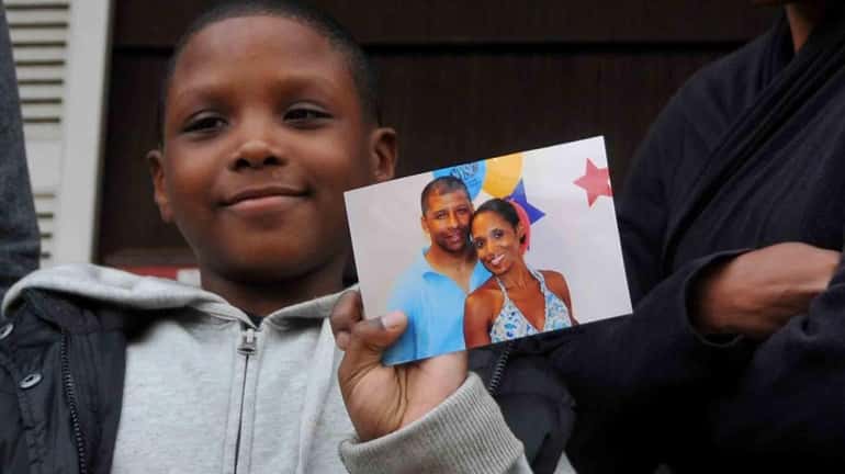 Joshua Menzies, 9, holds a photo of his mom, Natacha,...