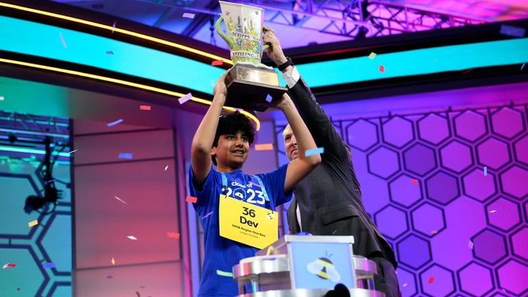 Dev Shah, 14, from Largo, Fla., lifts the trophy next...