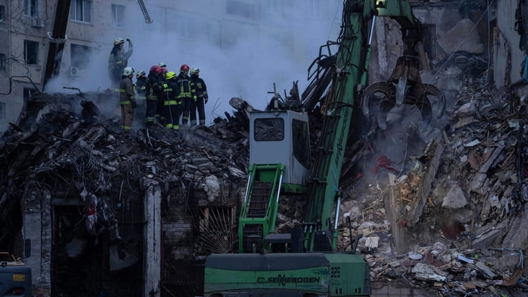 Rescue workers clear the rubble from an apartment building that...