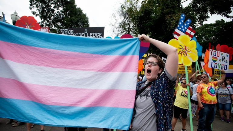 A supporter holds a transgender flag at the Gay Pride...