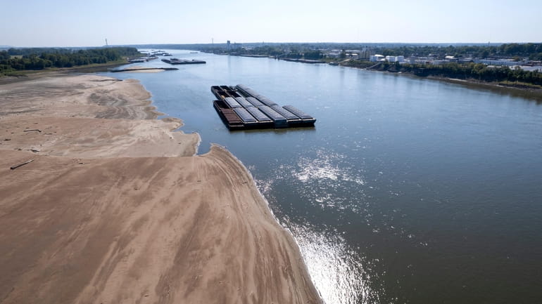 Barges float in the Mississippi River as a portion of...