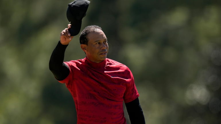 Tiger Woods tips his cap on the 18th green during...