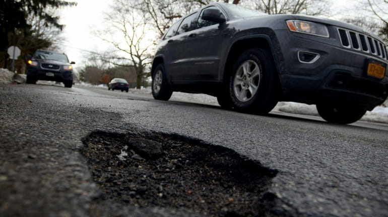 Cars drive past a pothole on Eastwood Blvd in Centereach...