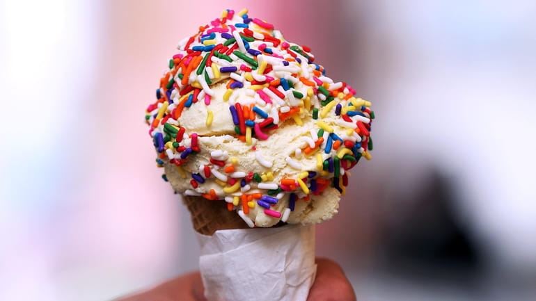 A scoop of vanilla ice cream with rainbow sprinkles is...