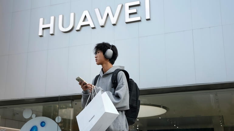 A customer carries his purchased Huawei product outside a Huawei...