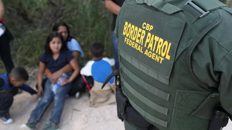 Central American asylum seekers wait as U.S. Border Patrol agents...