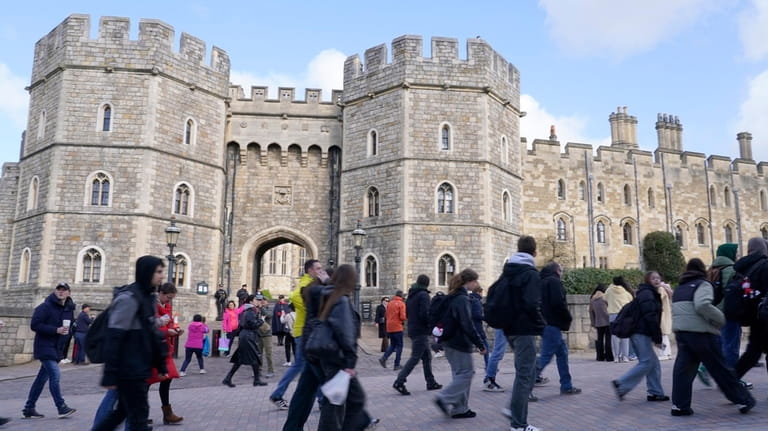People walk past Windsor Castle in Windsor, England, Saturday, March...