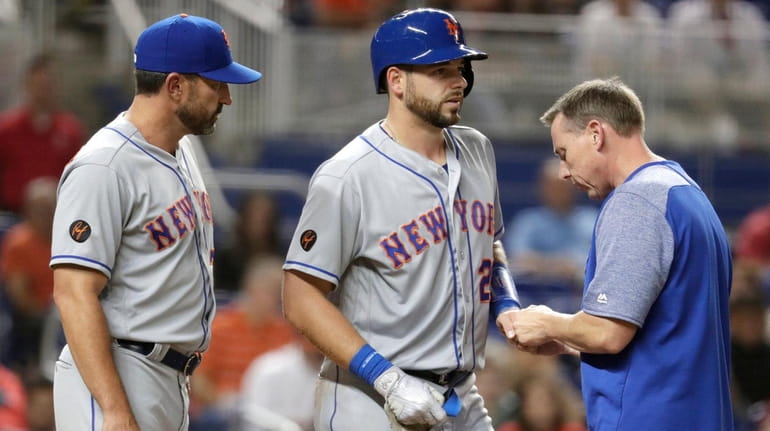 Mets catcher Kevin Plawecki has his hand looked at after...