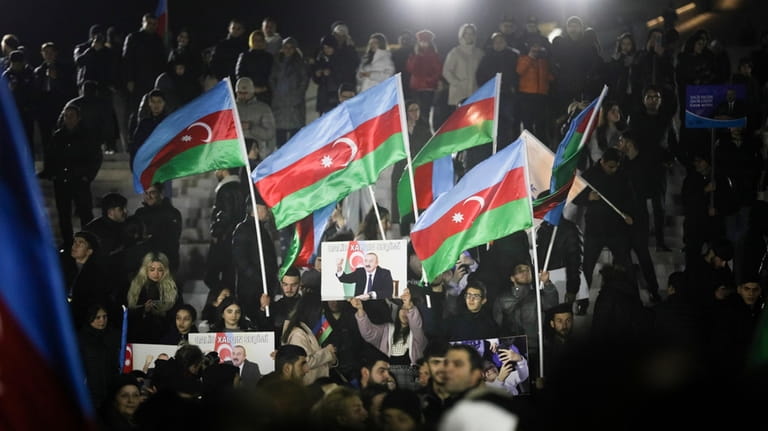People wave national flags celebrating Azerbaijan's President Ilhan Aliyev's victory...