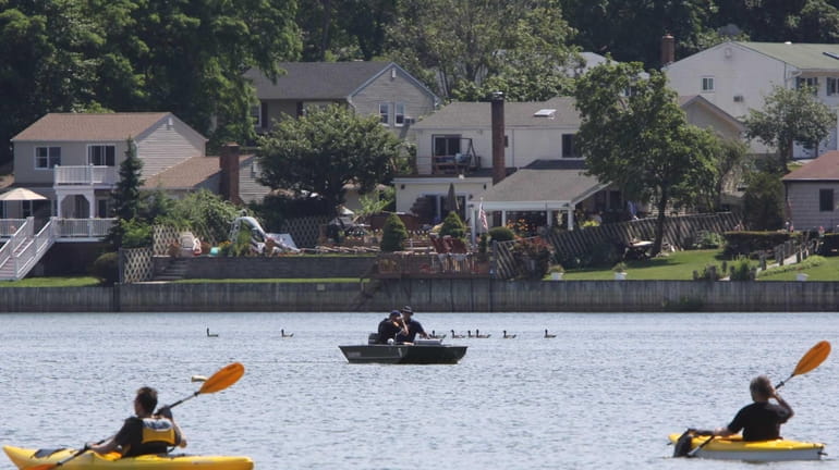 Kayakers paddle near members of the Suffolk County Police Department...