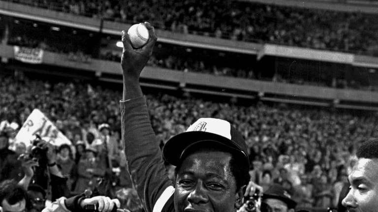 Hank Aaron holds aloft the ball he hit for his...