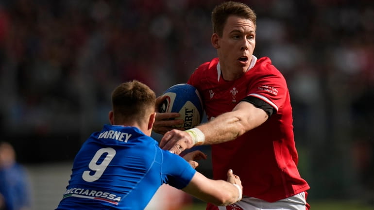 Wales' Liam Williams hands off Italy's Lorenzo Cannone to his...