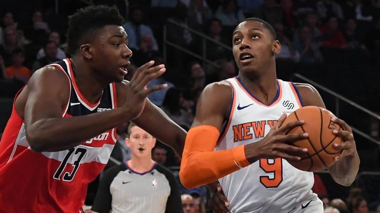 The Knicks' RJ Barrett drives to the basket defended by Wizards...
