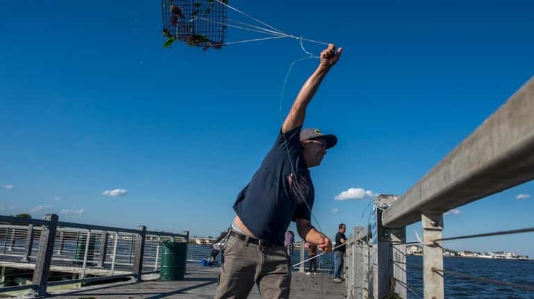 Raul Arbuckle, of Copiague, tosses out a crab trap at...