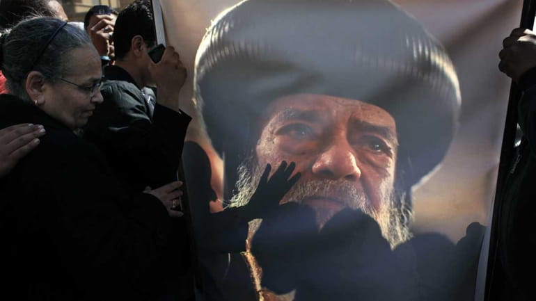 Egyptian Coptic mourners kiss a picture of the late Pope...