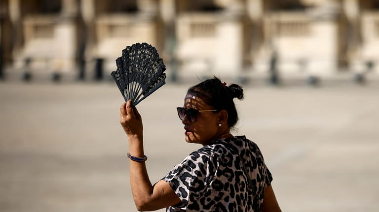 A woman uses a fan in the courtyard of the...