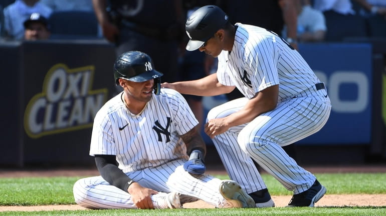 The Yankees' Gleyber Torres is assisted by third base coach...