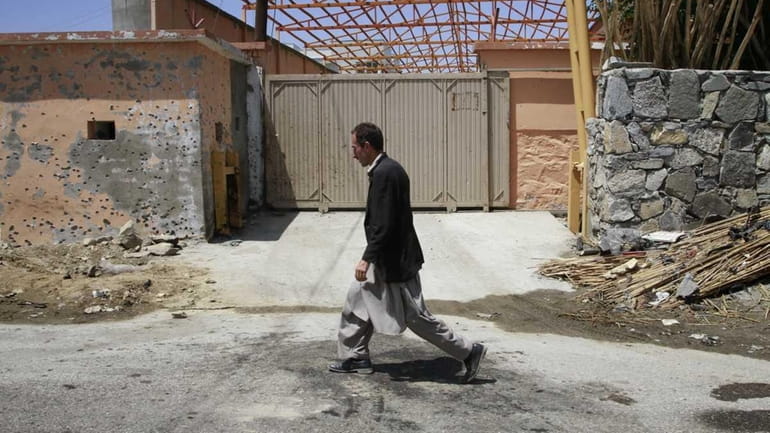 In this file photo an Afghan man walks past the...