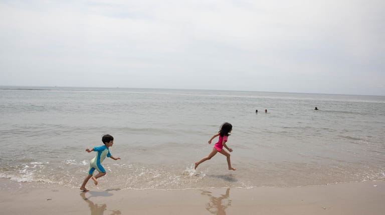 Children play on the shoreline at Jacob Riis Park in...
