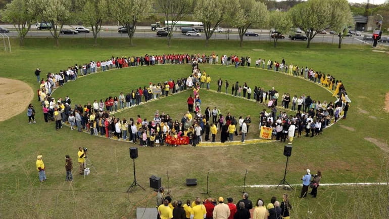 Kids, teachers and parents form a human peace sign in...