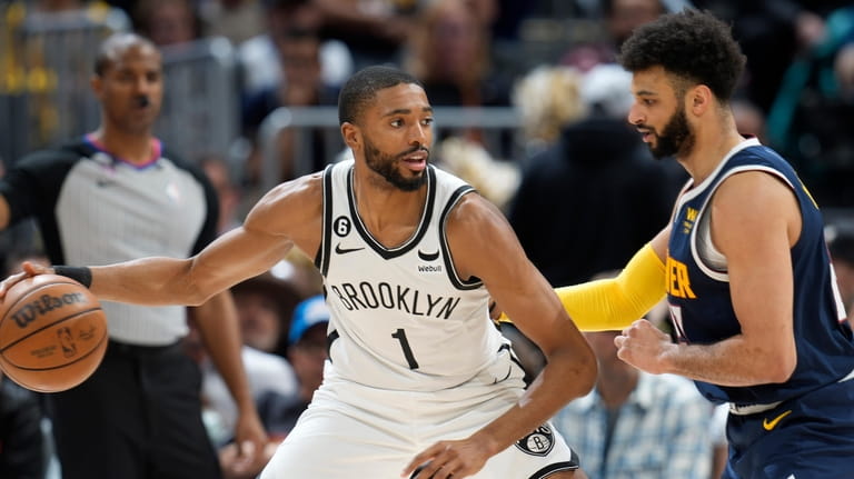 Nets forward Mikal Bridges, left, looks to drive to the...