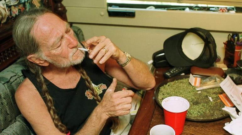 Willie Nelson takes a drag off a joint while relaxing...