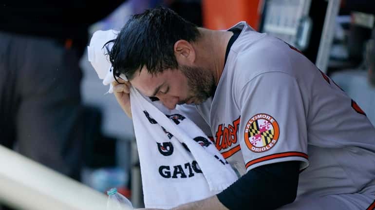 Orioles starting pitcher Matt Harvey wipes his face with a...