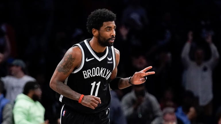 Nets' Kyrie Irving reacts after hitting a basket against the...