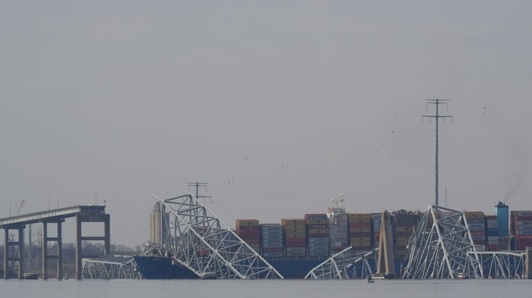 A container ship rests against wreckage of the Francis Scott...