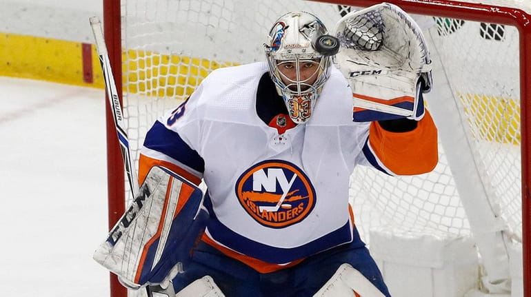 Islanders goaltender Christopher Gibson, top, gloves a shot by Pittsburgh...