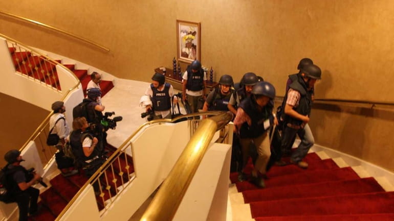 Foreign journalists in protective gear are seen climbing the stairs...