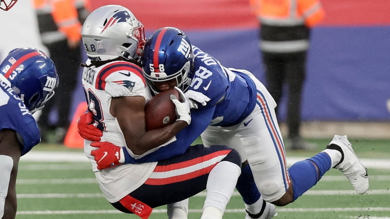 Bobby Okereke of the Giants tackles Rhamondre Stevenson of the Patriots during the fourth...