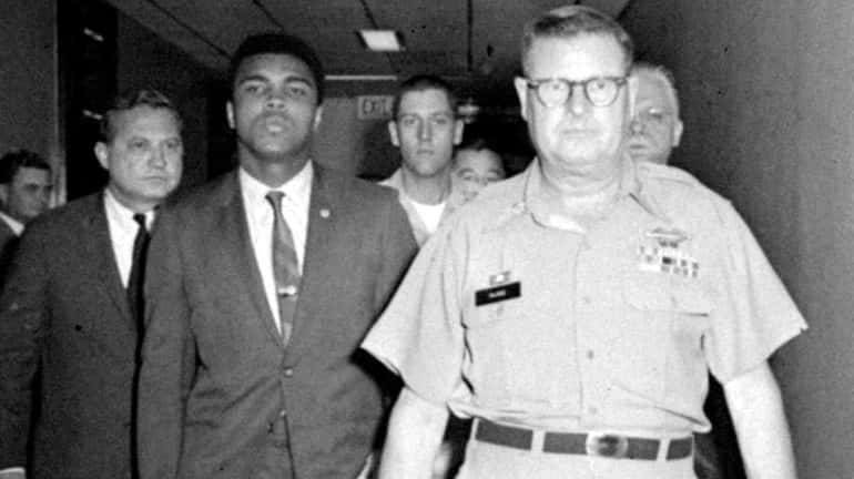 Heavyweight champion Muhammad Ali is pictured being escorted from the...